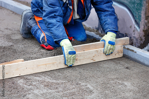 Wallpaper Mural The worker, sitting on his knees, manually levels the sandy base with a wooden board for future sidewalk cladding. Torontodigital.ca