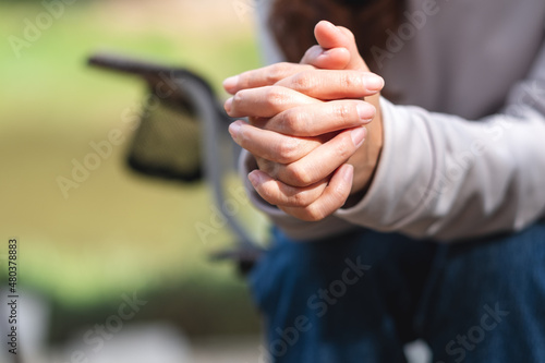 Closeup image of a woman with folded hands on knees while thinking  waiting  praying or making decision