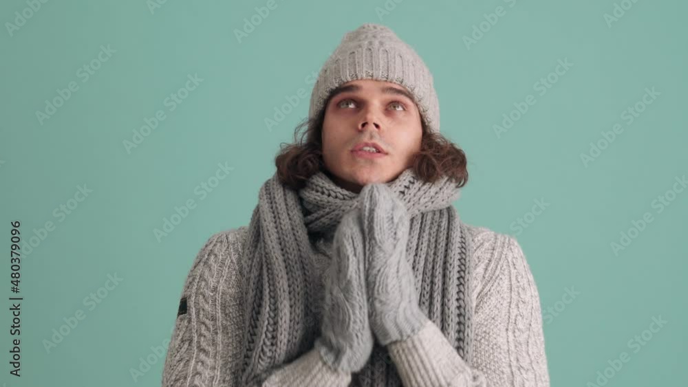 Handsome man in hat is cold in blue studio Handsome man in hat is cold in blue studio