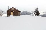 Remote single wooden house surrounded by white snow