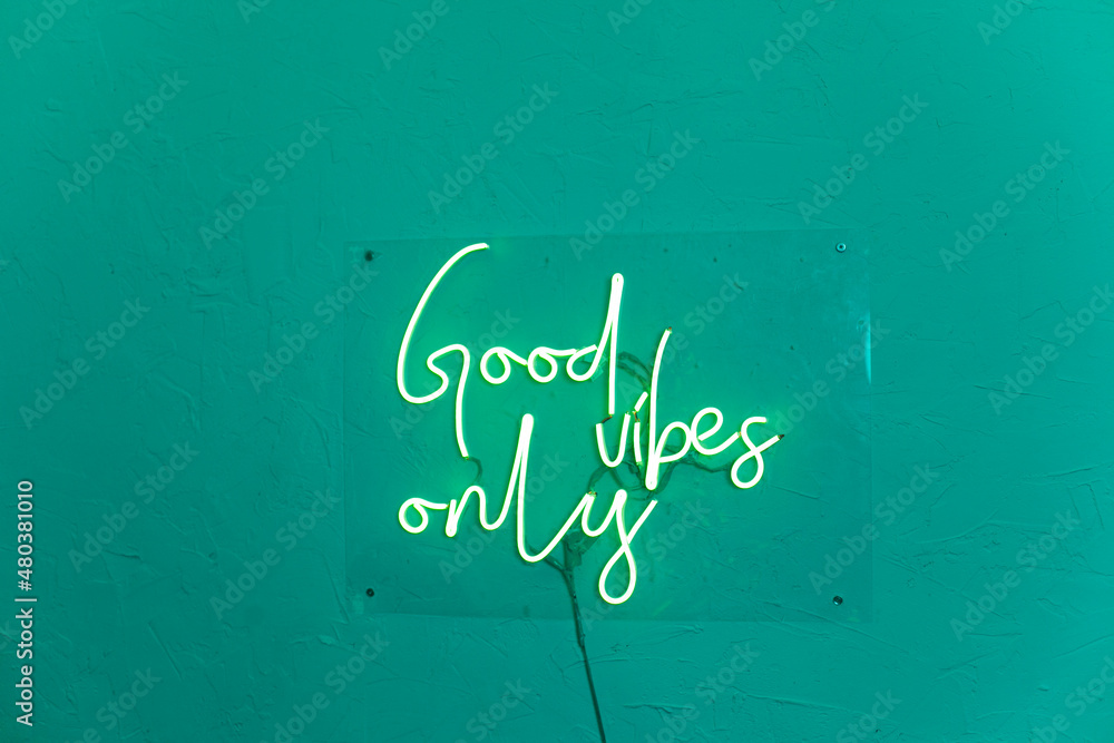 Neon words on the turquiose wall. Good vibes only neon sign at the bar, cafe or at home.