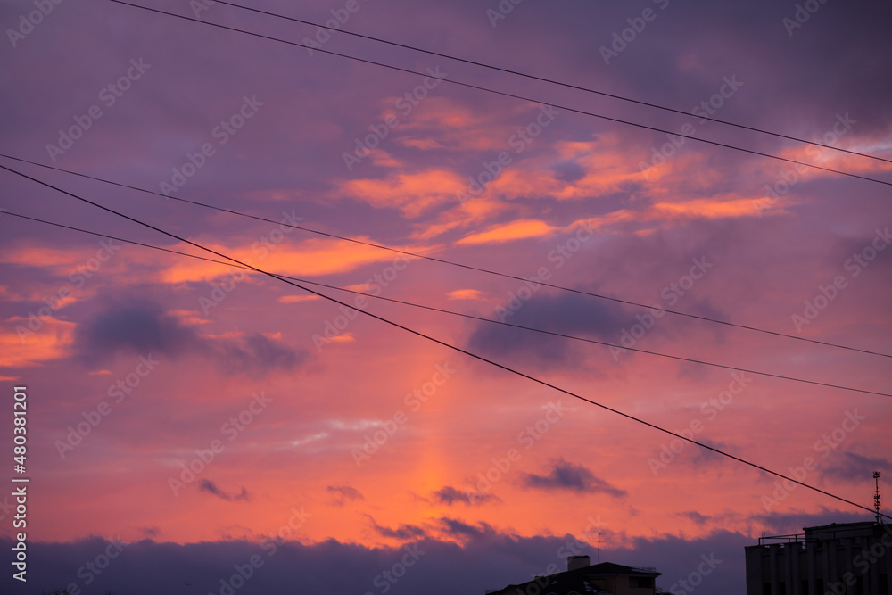 Bright colorful sunset through the wires over the city with dark silhouettes of the buildings. Horizontal sky backgroud at sunset or sunrise Bright colorful sunset through the wires over the city with dark silhouettes of the buildings. Horizontal sky backgroud at sunset or sunrise