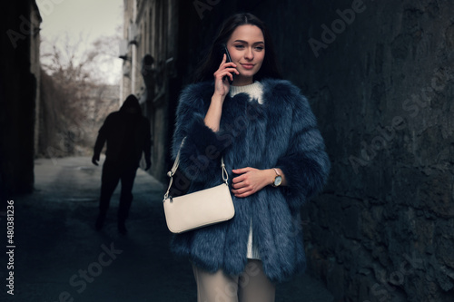 Quadro su tela Man stalking young woman while she talking on phone in alley
