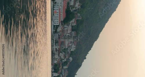 vertical long shot across the water to the beautiful town of Perast in Montenegro. City in the mountains. Bay of Kotor. reflection in water. vertical video