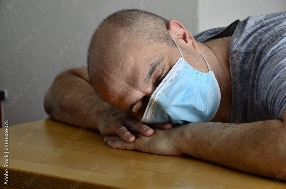 Obraz premium Man mit Maske schläft am Tisch
