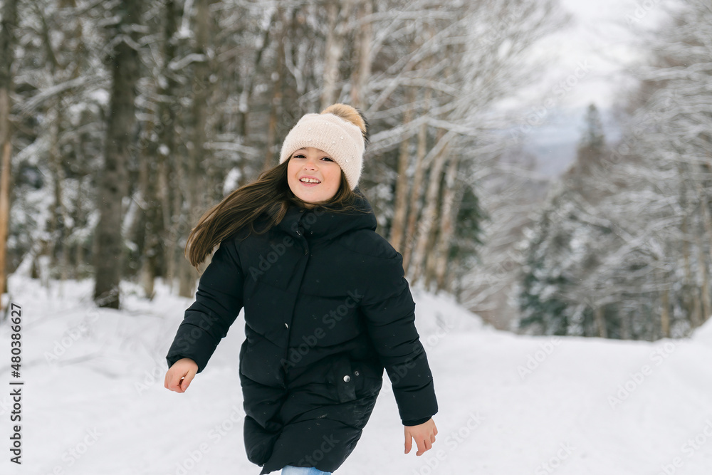 Beautiful child girl outdoors in winter. Snowing. Winter atmosphere Beautiful child girl outdoors in winter. Snowing. Winter atmosphere