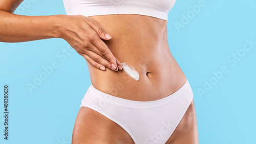Closeup of young woman apply lotion on her belly © Prostock-studio
