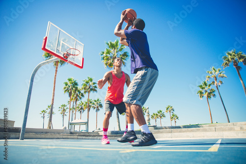 Young players playing basketball at the court in venice beach, California. Professional street ballers having fun performing tricks and huge slam dunks © oneinchpunch