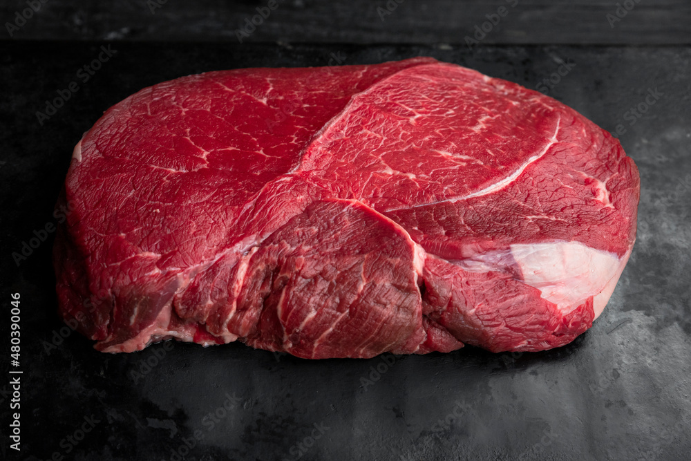 Raw beef steak on a dark slate background. Top view