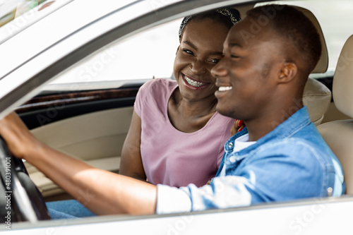 Loving black man and woman sitting inside new auto