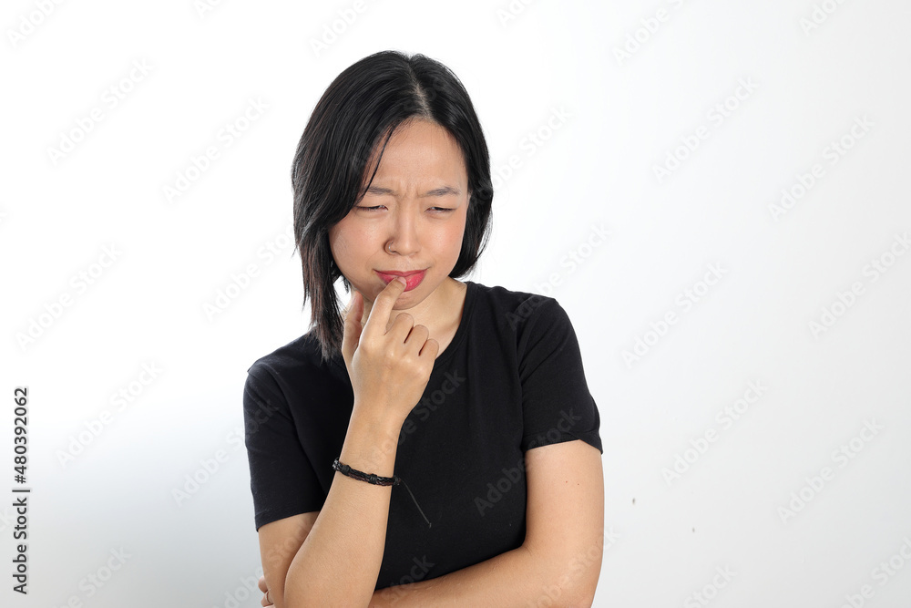 Young attractive south east asian woman pose face expression emotion on white background think finger in mouth Young attractive south east asian woman pose face expression emotion on white background think finger in mouth