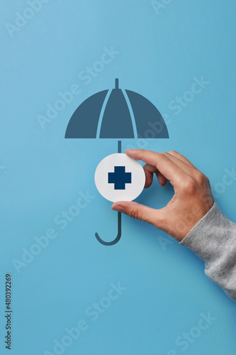 A medical cross and an umbrella over it. Symbol of health insurance and life protection