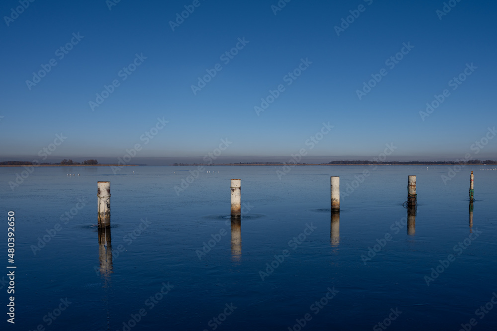A view of empty docks in the winter. Blue water and a clear blue sky