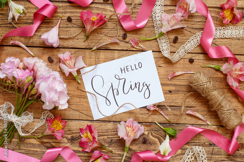 HELLO SPRING card between pink flowers on a wooden table photo