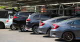 Closeup of gray car with other cars parking in outdoor parking area in bright sunny day. 