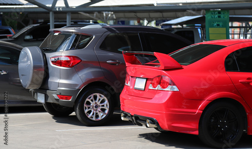 Closeup of red sedan car parking in outdoor parking area in bright sunny day. 