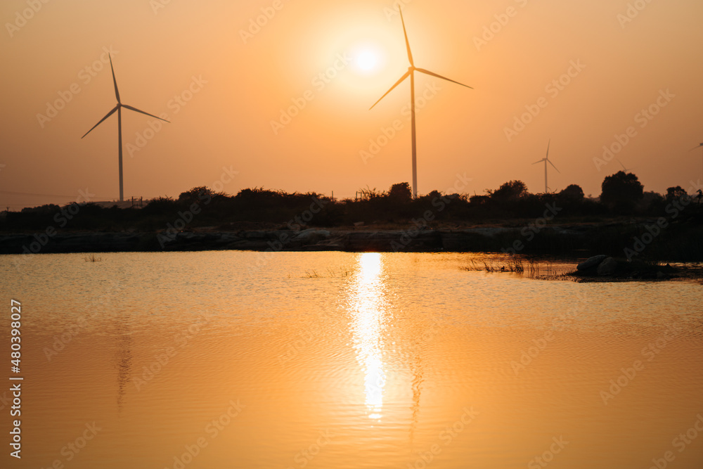 View of the sunset at the lake with windmills on the hills at Wankaner, Gujarat, India