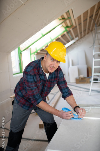 man on building site with yellow helmet works in drywall construction