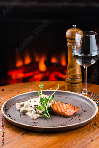 Organic baked salmon fillet topped with creamy mushrooms close-up on a plate