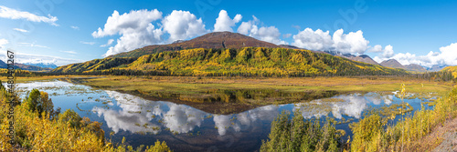 Reflection, nature shot in northern Canada, during fall in peak autumn colors with mountains reflecting in lake below. Blue sky on perfect day. 