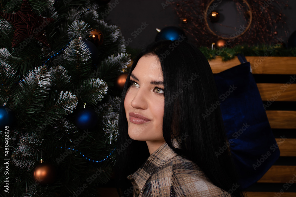 confident beautiful young woman in plaid shirt near christmas tree. new year, winter theme. confident beautiful young woman in plaid shirt near christmas tree. new year, winter theme.