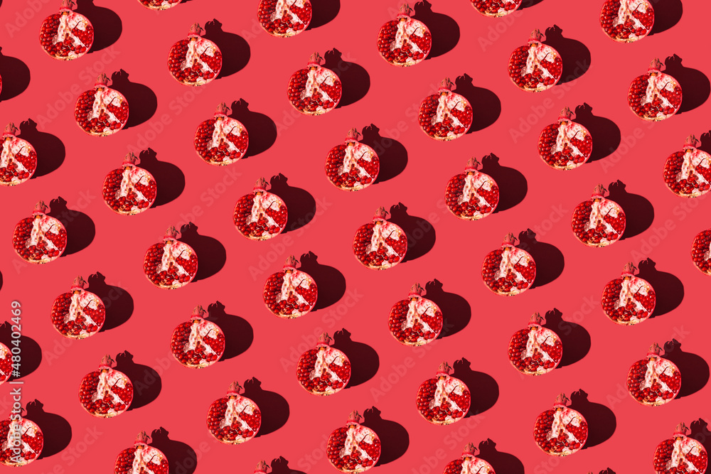 Creative pattern made of fresh pomegranate halves on red background with shadows. Minimal style. Top view. Flat lay . Creative pattern made of fresh pomegranate halves on red background with shadows. Minimal style. Top view. Flat lay .