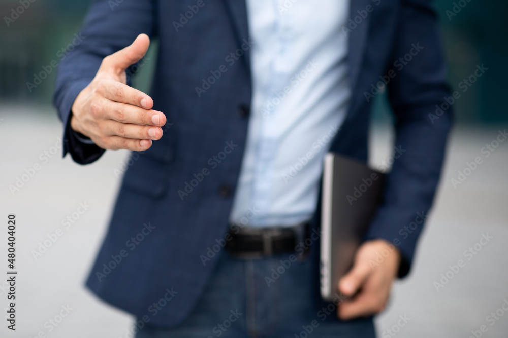 Fototapeta premium Unrecognizable businessman with laptop giving hand, greeting business partner