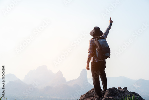 Success man hiker outstretched arms stand at cliff edge on mountain top with thumbs up to show that he is number one. Concept of adventure travel