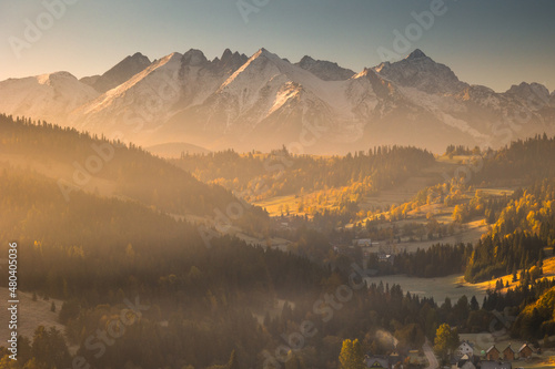 Autumn views of the Tatra Mountains from the surrounding hills. You can see the contrast between the snow above and the yellow leaves below. © PawelUchorczak
