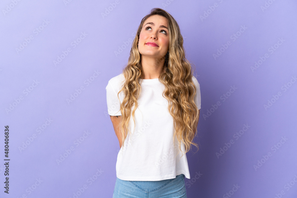 Young Brazilian woman isolated on purple background and looking up Young Brazilian woman isolated on purple background and looking up