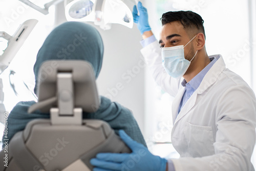Dentistry Concept. Arab Male Dentist Doctor Having Check Up With Muslim Woman