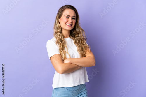 Young Brazilian woman isolated on purple background with arms crossed and looking forward