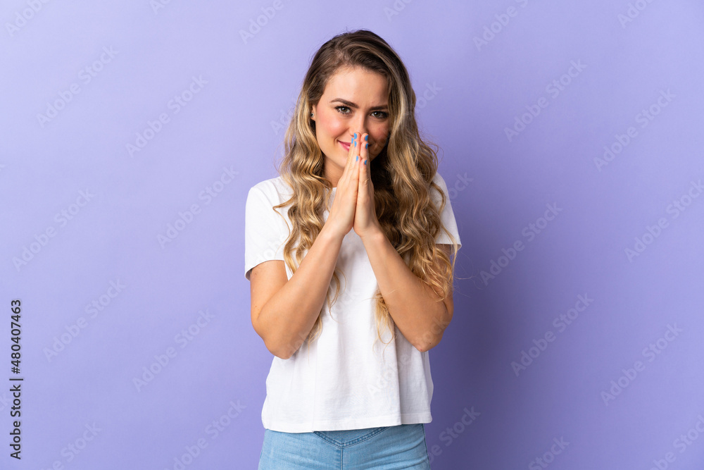 Young Brazilian woman isolated on purple background keeps palm together. Person asks for something Young Brazilian woman isolated on purple background keeps palm together. Person asks for something