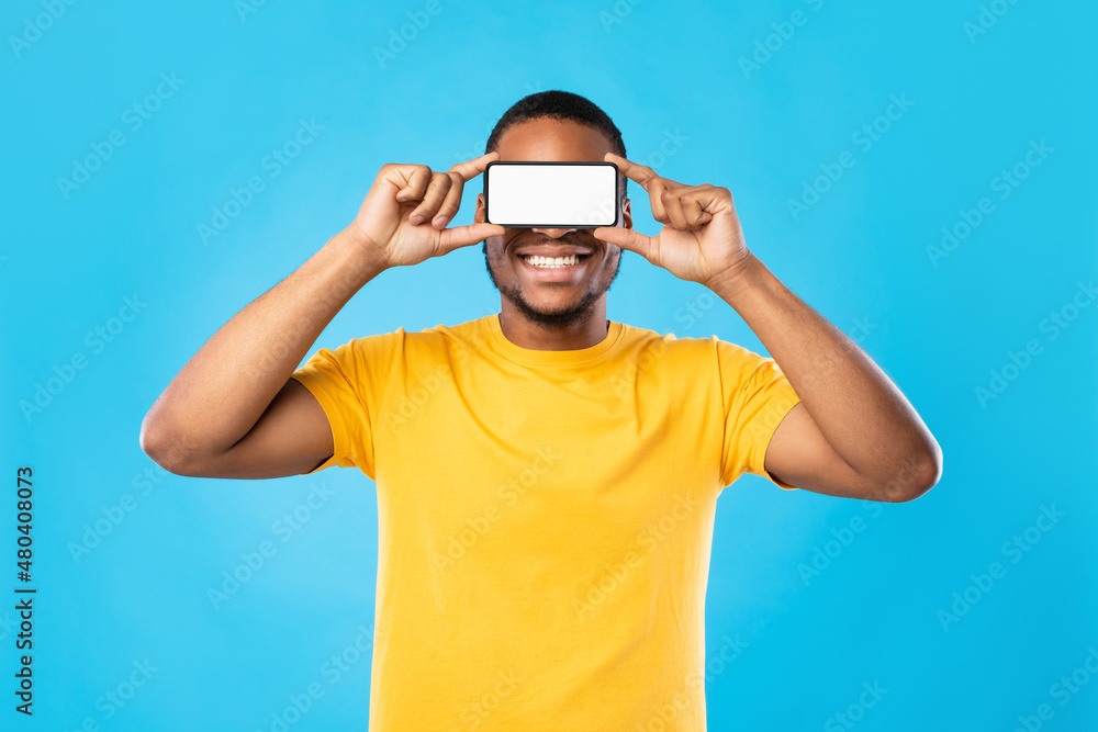 Black Man Holding Phone In Front Of Eyes, Blue Background Black Man Holding Phone In Front Of Eyes, Blue Background
