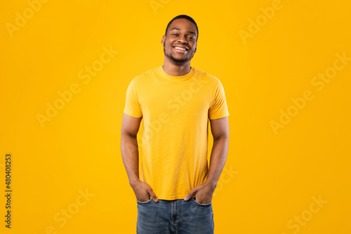 African American Man Posing Holding Hands In Pockets, Yellow Background