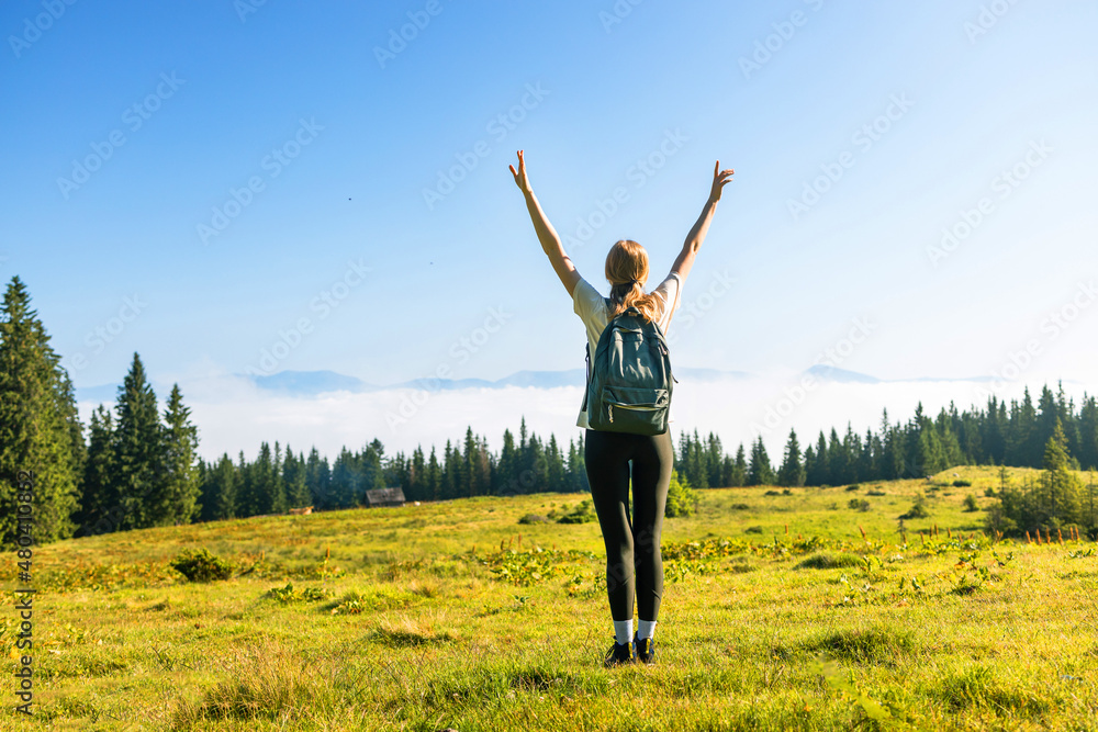 Amazing Carpathians landscape background banner panorama. Traveler with hiking backpack on mountain summit enjoying aerial view hands raised over clouds at a hot summer day Amazing Carpathians landscape background banner panorama. Traveler with hiking backpack on mountain summit enjoying aerial view hands raised over clouds at a hot summer day