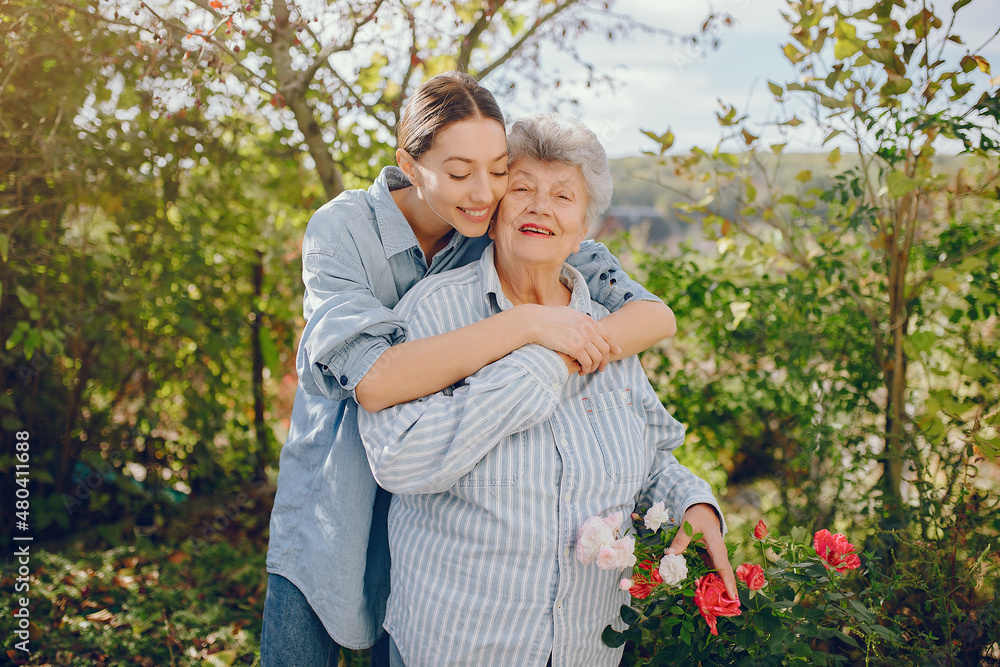 Old woman in a garden with young granddaughter Old woman in a garden with young granddaughter