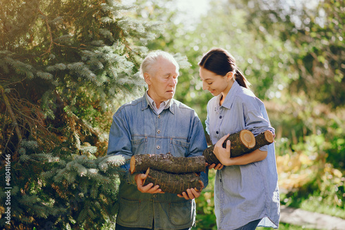Grandfather with granddaughter on a yard with firewood in hands photo