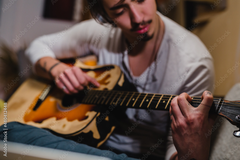 Obraz premium man playing acoustic guitar at home