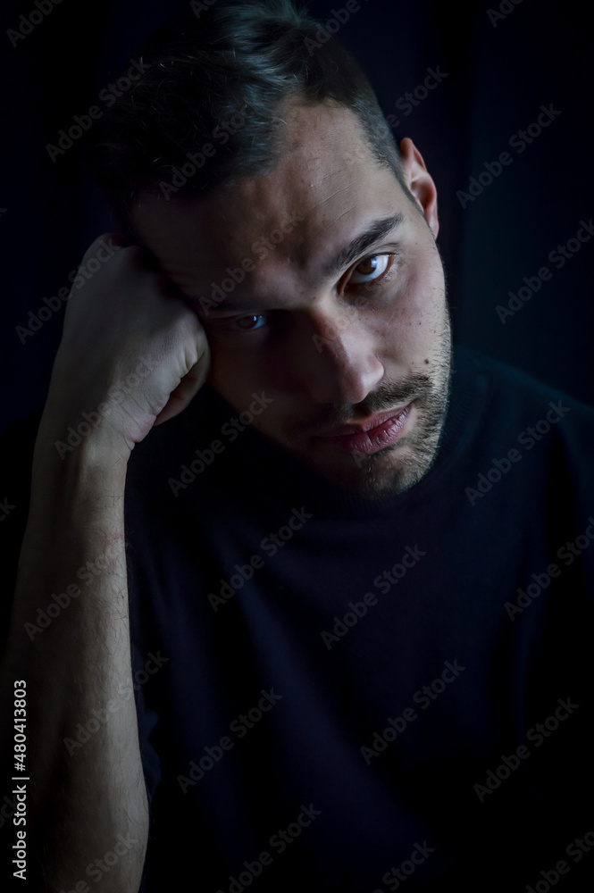portrait of a young man with his head resting on his fist looking very bored and depressed