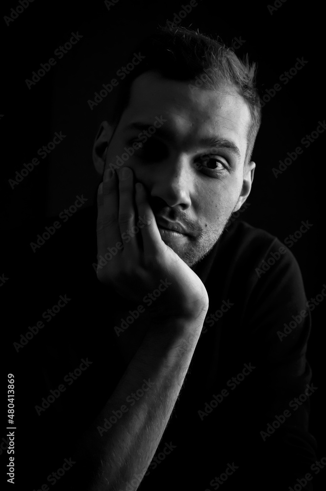 close up portrait in black and white of a young man holding his face in his hand and looking bored close up portrait in black and white of a young man holding his face in his hand and looking bored