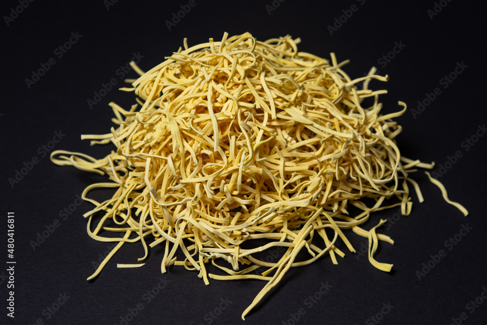Egg noodles on a black background. A bunch of dry noodles on a dark background. pasta