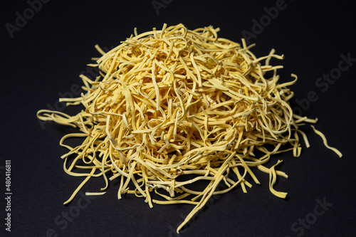 Egg noodles on a black background. A bunch of dry noodles on a dark background. pasta