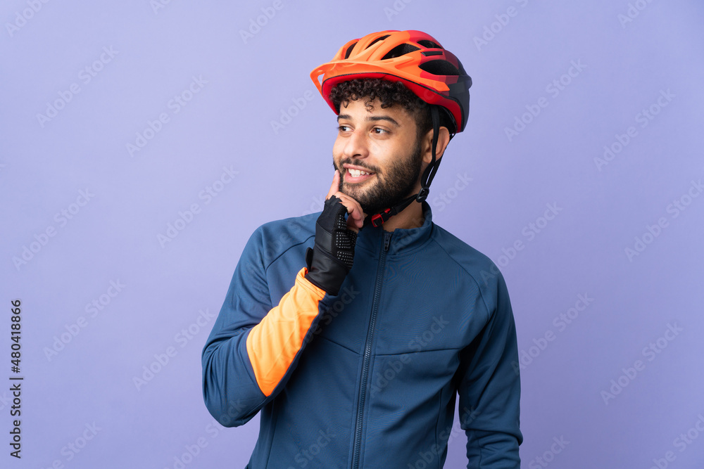 Young Moroccan cyclist man isolated on purple background thinking an idea while looking up Young Moroccan cyclist man isolated on purple background thinking an idea while looking up