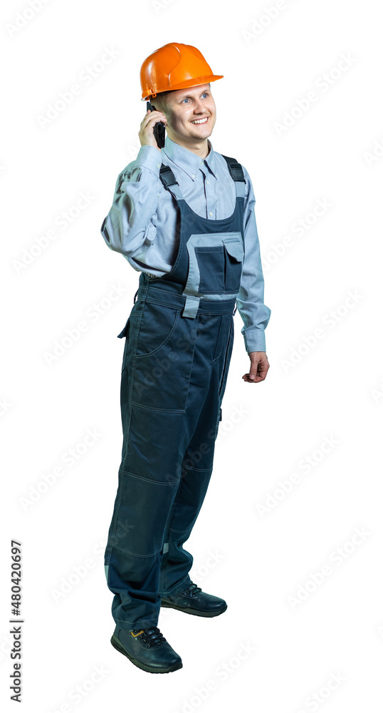 isolated. male engineer, builder in workwear and helmet emotionally speaks on the phone isolated. male engineer, builder in workwear and helmet emotionally speaks on the phone
