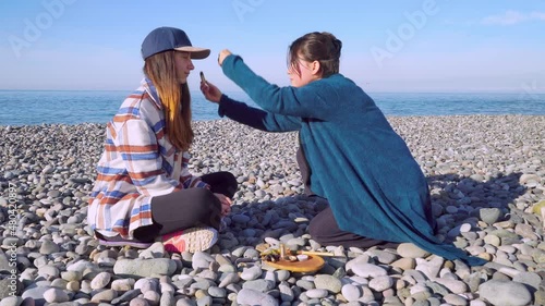 Two women are sitting on the seashore and preparing for the rapee ceremony. Esoteric objects for meditation. Antistress and relaxation. photo