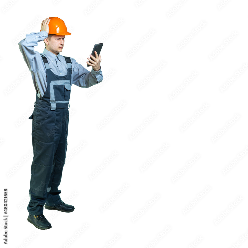 the worker holds a tablet in one hand, and holds his head with his other hand. male engineer frowns and look at the gadget isolated the worker holds a tablet in one hand, and holds his head with his other hand. male engineer frowns and look at the gadget isolated