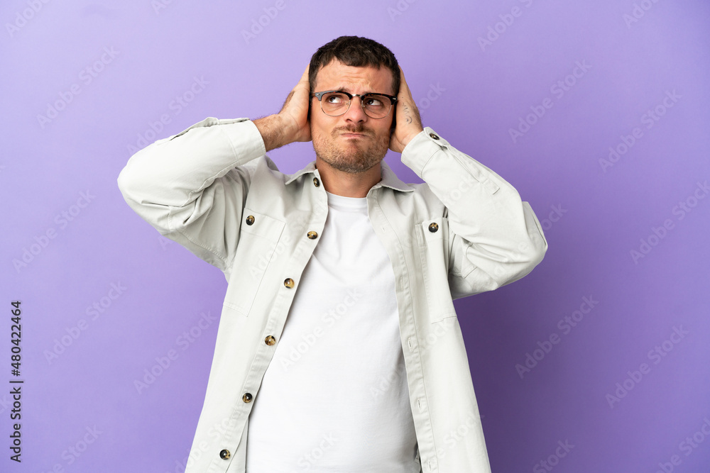 Brazilian man over isolated purple background frustrated and covering ears Brazilian man over isolated purple background frustrated and covering ears