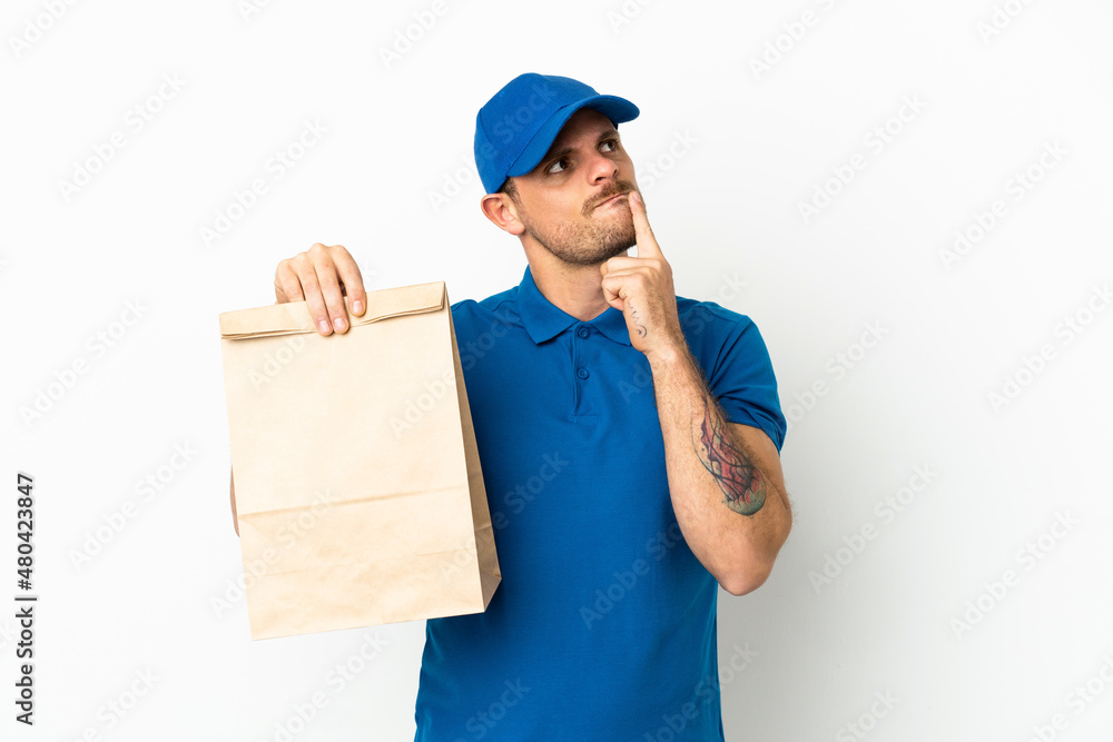 Brazilian taking a bag of takeaway food isolated on white background having doubts while looking up Brazilian taking a bag of takeaway food isolated on white background having doubts while looking up
