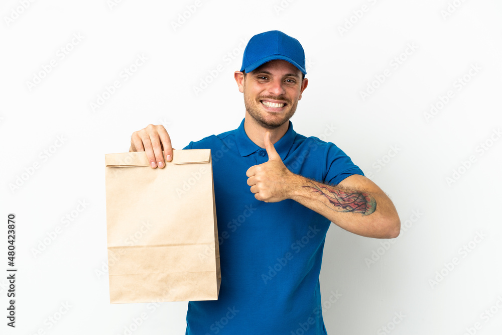 Brazilian taking a bag of takeaway food isolated on white background giving a thumbs up gesture Brazilian taking a bag of takeaway food isolated on white background giving a thumbs up gesture